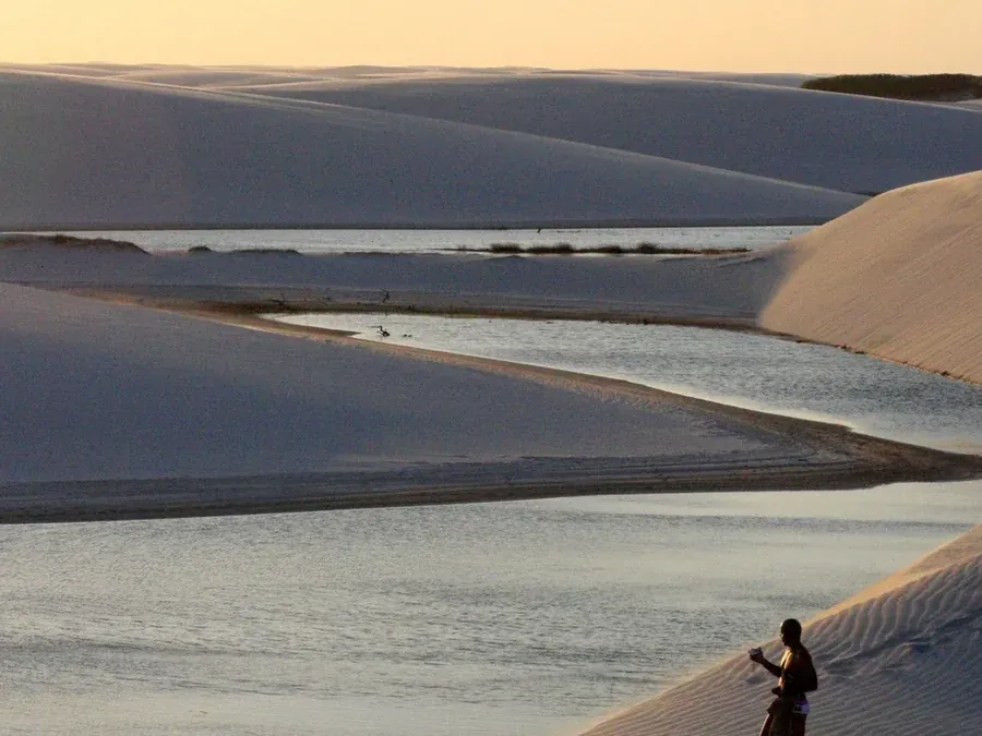 Dunas douradas ao fim da tarde com uma lagoa entre elas, em Atins