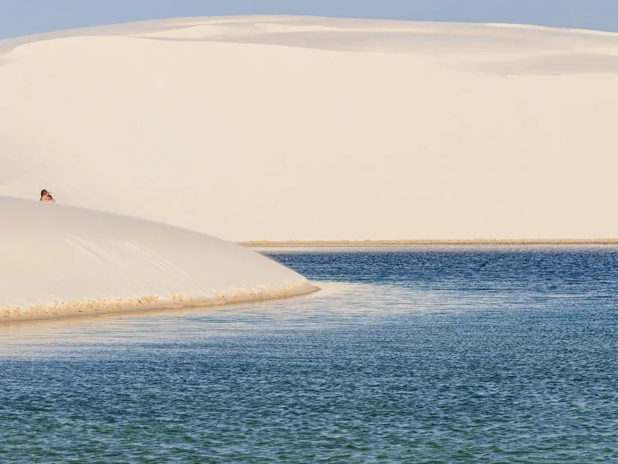Duna branca e lagoa azul aberta sob o céu limpo em Atins