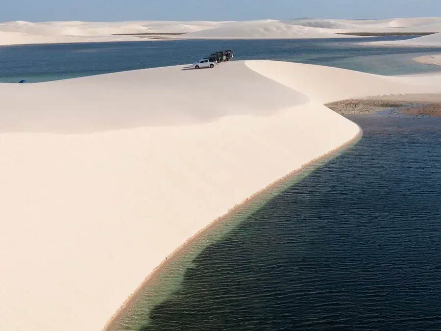 Faixa de duna branca dividindo uma lagoa escura e profunda em Atins