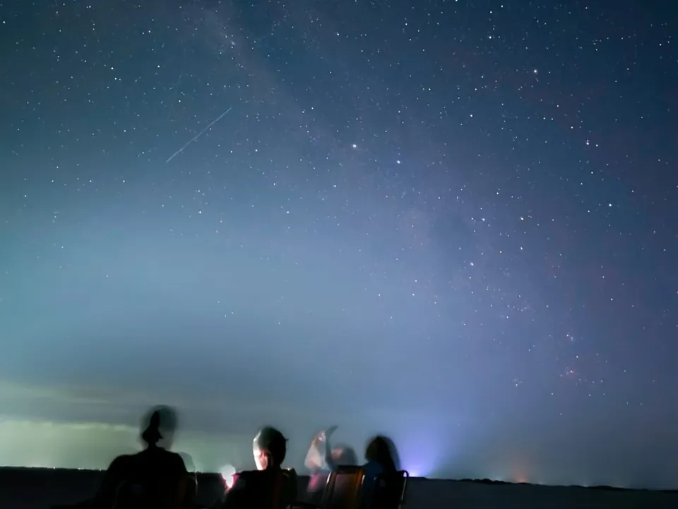 Grupo sentado em cadeiras sob o céu estrelado dos Lençóis Maranhenses