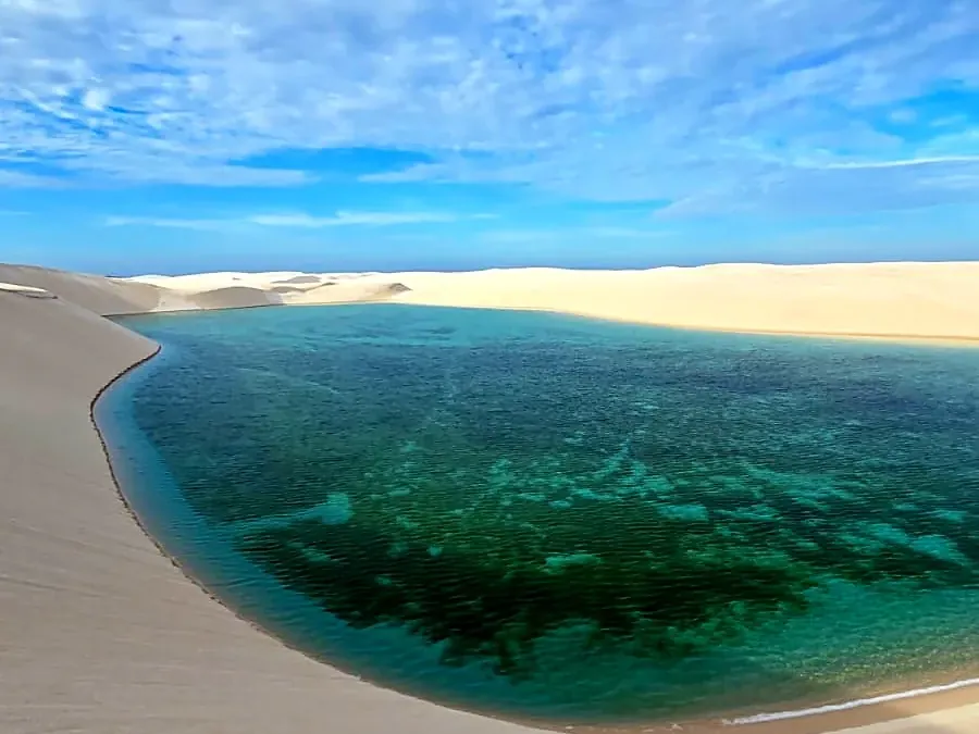 Grande lagoa turquesa curvando entre dunas brancas