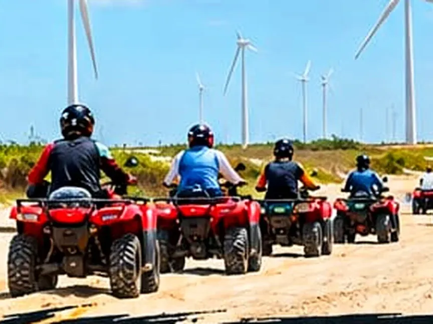 Fila de quadriciclos vermelhos seguindo pela areia da praia dos Pequenos Lençóis