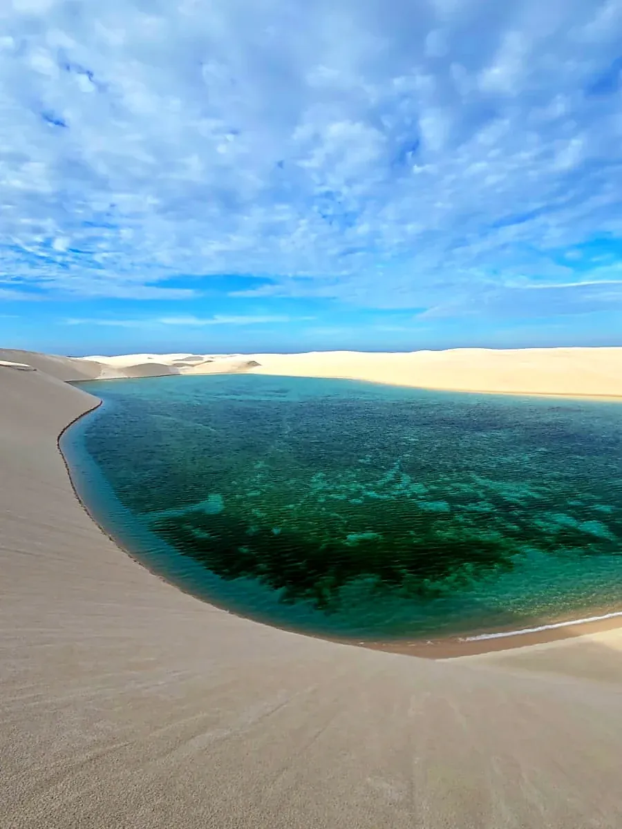 Grande lagoa turquesa curvando entre dunas brancas